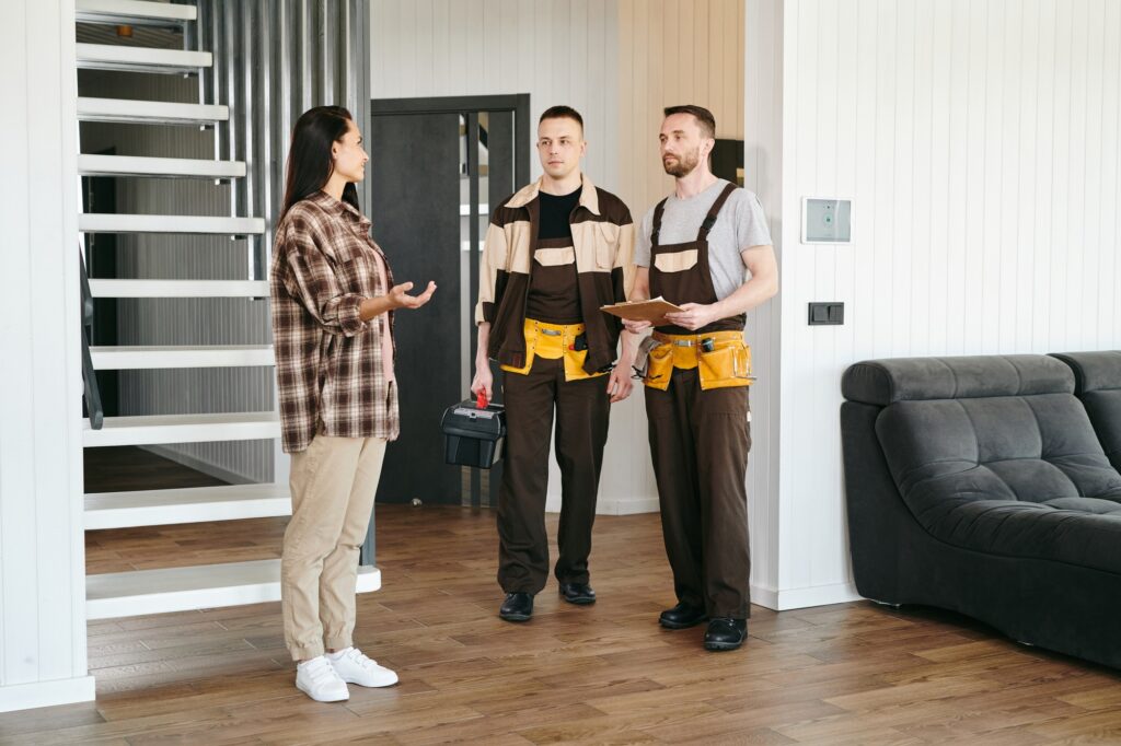 Two plumbers and young female having conversation about plumbing problems