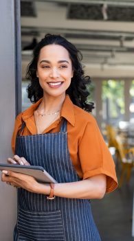 Small business entrepreneur at cafe entrance using digital tablet